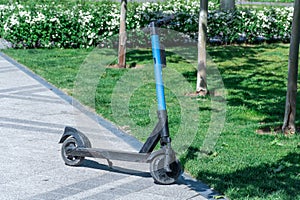 Electric scooter parked on sidewalk in city. Public mobile transport standing.