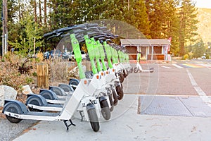 Electric scooter for sharing parked along a street in a mountain resort in autumn