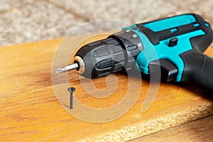 Electric screwdriver near the screw screwed into the chipboard