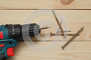 Electric screwdriver on a wooden table. Side view of the black metallic screws, electric screwdriwer on the wodden boards