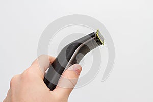 Electric shaving trimmer in hand on white background