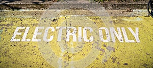 Electric Only sign painted on sidewalk, parking and charging station area for electric vehicles