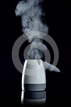 Electric small kettle with boiling water on black