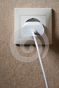 Electric socket on a pink wall. The black wire plug is connected. Renovated backdrop of studio apartment. Blank copy