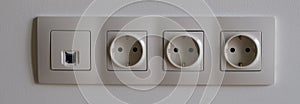 Electric socket on white wall closeup. Sockets with antenna cable and internet