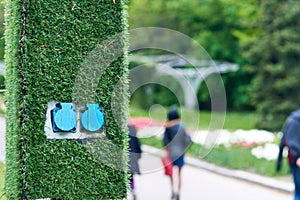 Electric sockets for charging on a pole with artificial green grass in the park