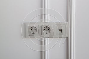 Electric sockets and Internet socket in champagne color on the wall with boiserie