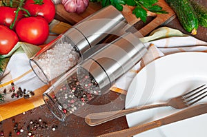 Electric spice mills. With Himalayan salt and pepper. Lie on the table. Nearby are cutlery and vegetables