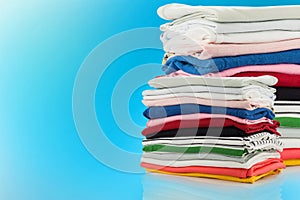 Electric steam iron and Pile of colorful clothes isolated on blu