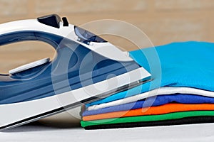 Electric steam iron and a stack of ironed t-shirts