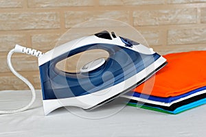 Electric steam iron and a stack of ironed t-shirts