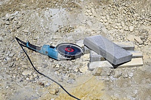 Electric tool with diamond disc for cutting stones lies on gravel. Angle grinder is ready for operation. Stone cutting technology