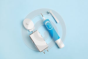 Electric toothbrush and accessories on a blue background. view from above. charger and replaceable nozzle