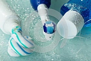 Electric toothbrush, paste and mouthwash, on wet glass shelf