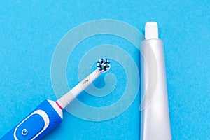 Electric toothbrush and toothpaste. Blue background. Flat lay. The concept of modern dental care products