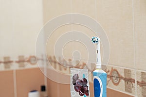electric toothbrushe and toothpaste on blurred background at bathroom