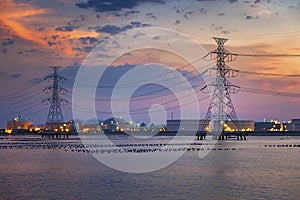 Electric towers and refinary oil storage plant in twilight