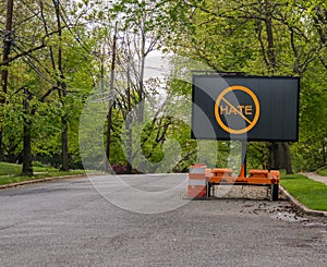 Electric traffic street sign on quiet neighborhood street that has a no hate symbol.