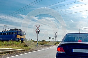 The electric train approaching railroad crossing. Car standing in front of the railway crossing without a barrier