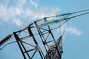 Electric transmission line tower with insulators and conductors. Closeup view on blue sky background. Concept of electric power