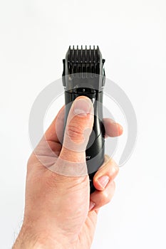 Electric trimmer in a manÃ¢â¬â¢s hand on a white background