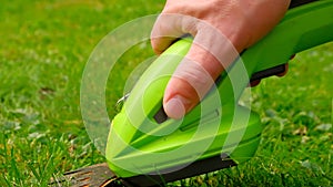 electric trimmer in a mans hand close-up cuts the grass.lawn trimmer.The process of cutting grass close-up.Garden
