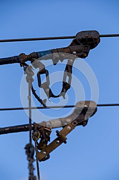 Electric trolleybus collectors close-up against the April blue spring sky. Power line wires network. Public transport.