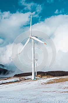 Electric Turbine Windmill on a blue sky and snowy ground. Closeup image of turbines blades on a hill full of snow