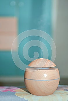 An electric ultrasonic humidifier that emits atomized water droplets. The device is round in shape with a wooden body. Relaxation