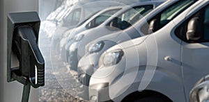 Electric vehicles charging station on a background of a row of vans photo