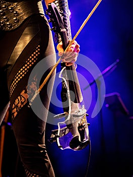 Electric violin in the hands of a beautiful woman musician, rock concert