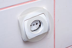 An electric white plastic outlet inwardly cracked cracked along the mount