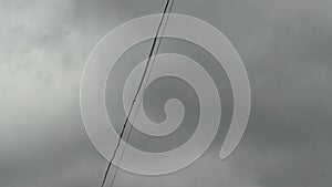 Electric wires stagger in the strong wind of a hurricane against the background of gray thunderclouds. Copy space for