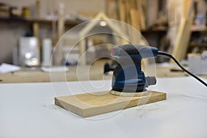 Electric Wood Sander on wooden table in workshop. Woodworking tool concept. Furniture metal polisher, dander DIY power-tools