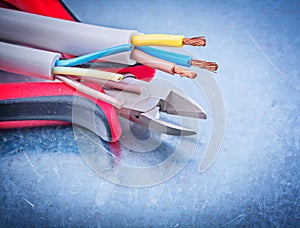 Electrical cables wires cutting pliers on metallic background co