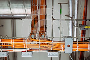 Electrical conduits system and metal pipeline installed on building ceiling, orange wires