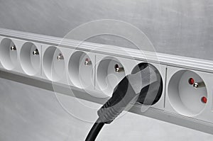 Electrical cord with power strip on grey metal background