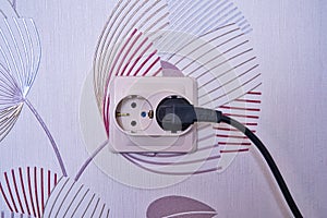 Electrical double socket close-up. Double socket with plug inserted on a pale orange wall, space for text. Electricity