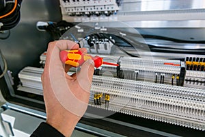 Electrical engineer checking electric cubicle and fixing connector strips.