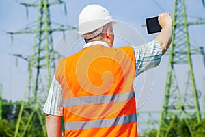 Electrical engineer filmed with tablet PC near high voltage power line