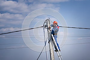 Electrical engineer performs wiring on a high pole standing on the stairs. high-rise electrical work. podkluchenie house to the