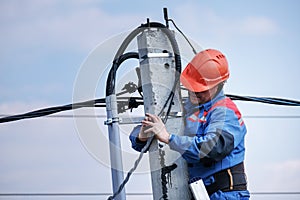 Electrical engineer performs wiring on a high pole standing on the stairs. high-rise electrical work. podkluchenie house to the