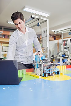 Electrical engineer programming a robot during robotics class