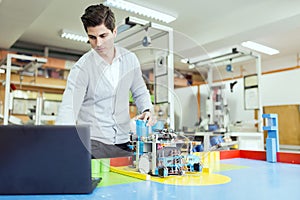 Electrical engineer programming a robot during robotics class