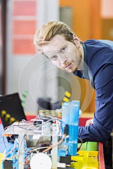 Electrical engineer programming a robot during robotics class