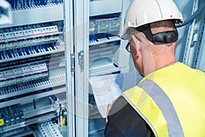 An electrical engineer reads a wiring diagram in a control cabinet