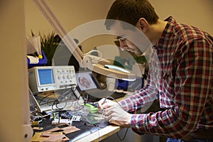 Electrical Engineer Soldering Circuit Board At Work Bench