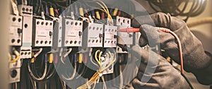 Electrical engineer using digital multi-meter measuring equipment to checking electric current