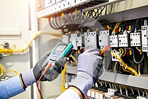 Electrical engineer using digital multi-meter measuring equipment to checking electric current voltage at circuit breaker and