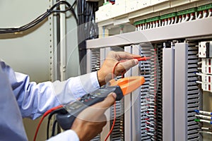 Electrical engineer using digital multi-meter to check current voltage